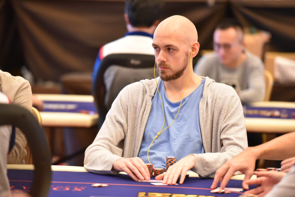 Bald man sitting at a poker table during a live tournament